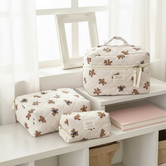 3 different sized teddy bear bags sat on a desk near a white window with a picture frame and pink book